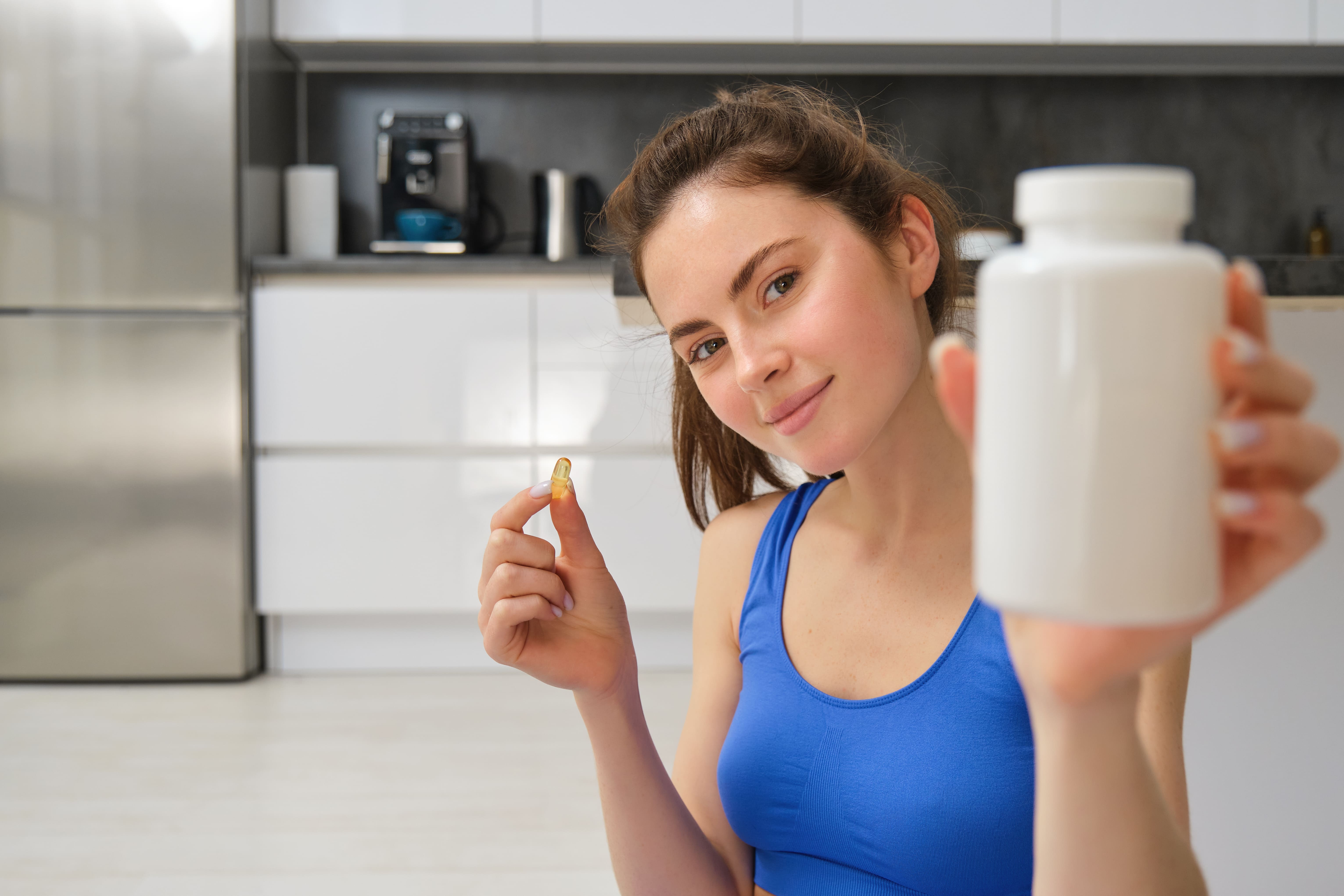 close-up-portrait-young-woman-fitness-instructor-showing-bottle-vitamins-taking-buds (1).jpg